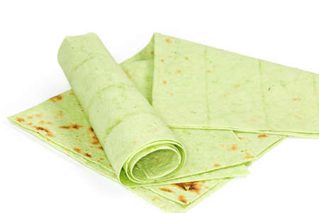 Two folded and twisted thin flat unleavened breads, also known as lavash prepared with spinach on a white background, close-up in selective focusの写真素材