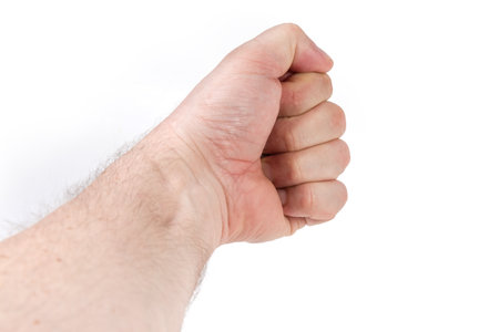 Left hand of adult man outstretched forward away from yourself with all fingers tightly clenched into a fist, situated with thumb up on a white backgroundの写真素材
