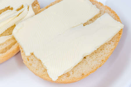 Open sandwiches made with halves of small round bun and slices of butter on dish close-up