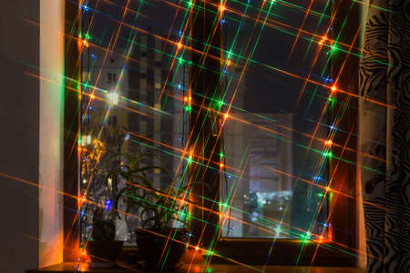 Part of the modern wooden window decorated with electric garland of varicolored Christmas lights in...