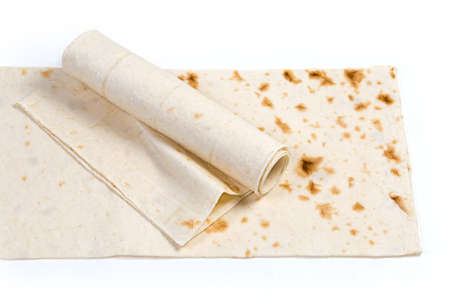 Twisted in roll thin flat unleavened breads, also known as lavash lies on the other same folded lavash on a white backgroundの写真素材