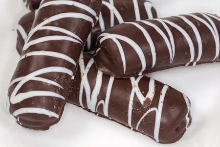 Cookies glazed with dark chocolate and transverse strips of white chocolate on the white surface,...