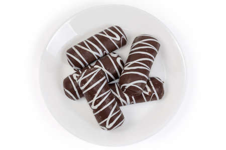 Cookies glazed with dark chocolate and transverse strips of white chocolate on the white dish on a...