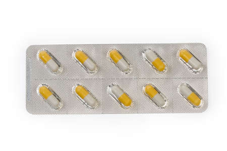 Blister pack with white-yellow pills of pharmaceutical product on a white background, top view