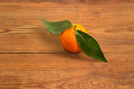 Single tangerine on a small twig with leaves on the old rustic tableの写真素材