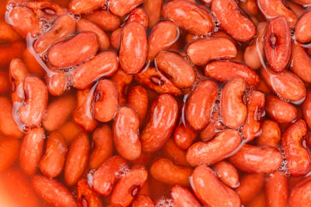 Raw red kidney beans soaked in cold water before preparation for the faster cooking, top view