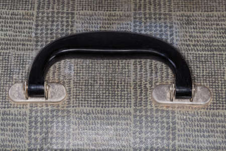 Handle made with plastic and metal of the old fashioned shabby gray leatherette hardshell suitcase, top view close-upの写真素材