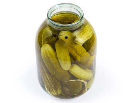 Canned cucumbers with spices in big glass jar with removed lid on a white backgroundの写真素材