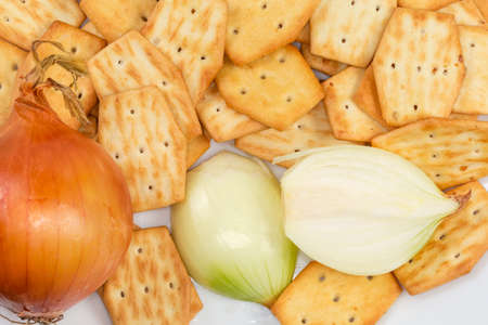 Savory crackers with onion addition when preparing and fresh onion bulbs, top view close-upの写真素材