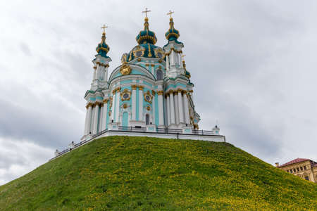 Baroque church Saint Andrew's of the 18th century on the hill covered with flowering dandelions, bottom up view against the cloudy sky, Kyiv, Ukraineの写真素材