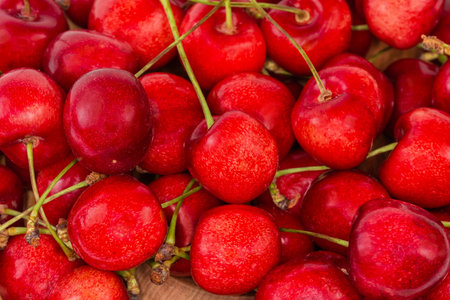 Red sweet cherries with the stems on a heap, top view close-up, background