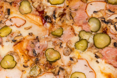 Surface of the pizza with different ham, mushrooms and pickled cucumbers, top view of pizza fragment, backgroundの写真素材