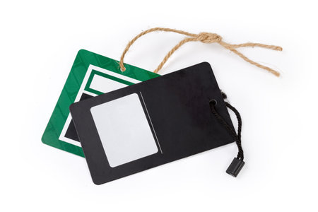 Blank clothing swing tags in the form of the black and green carton sheets on the ropes on a white backgroundの写真素材