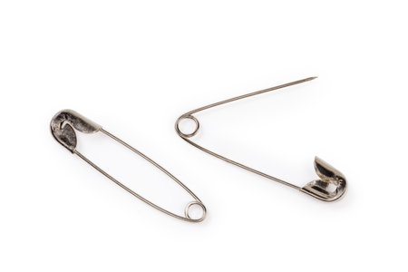 One open and one closed metal safety pins, top view close-up on a white backgroundの写真素材