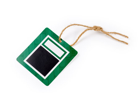 Blank clothing swing tag in the form of black and green carton sheet on a brown rope on a white backgroundの写真素材