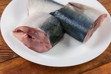 Raw pieces of the chilled Japanese amberjack or yellowtail on a white dish, close-up in selective...