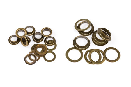Heaps of the metal shaped sleeves and washers as eyelets components two different sizes before installation, view on a white backgroundの写真素材