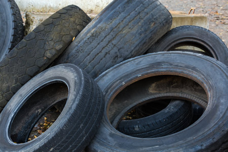 Heap of the different old used truck and car tires with worn treads, some of them are torn outdoors, fragment close-upの写真素材
