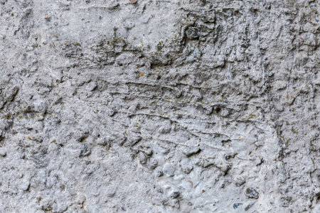 Fragment of the old concrete wall with a rough surface, outdoors in overcast weather, background, textureの写真素材