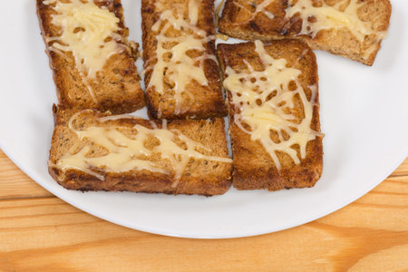 Hot open sandwiches made with small slices of brown grain bread and grated cheese on the dish on a...