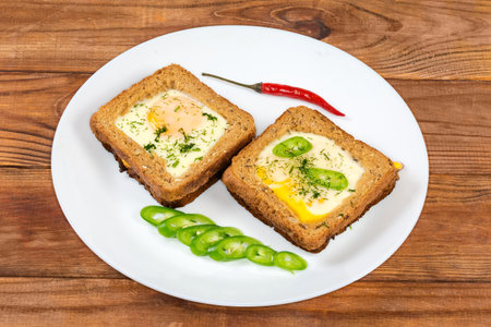 Two open sandwiches made with fried egg prepared sunny side up and whole wheat bread for toast on a...