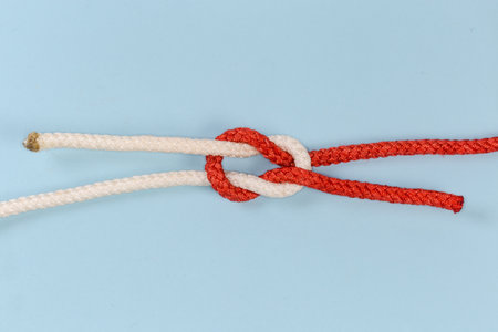 Rope grief knot, similar to reef knot, but impractical and used as device for trick, view on a blue...