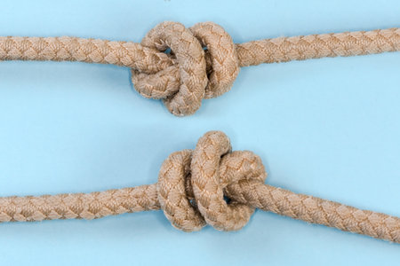 Tightened rope Stevedore knot tied with a climbing rope, view from two sides close-up on a blue...