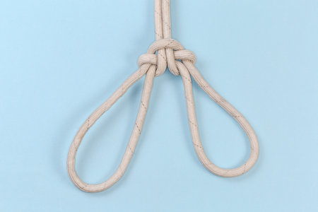 Rope knot Spanish bowline intended to lift a person, view from behind on a blue background
