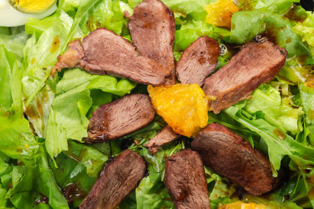 Salad made with boiled duck meat, egg, orange slices and different greens, top view of fragment close-upの写真素材