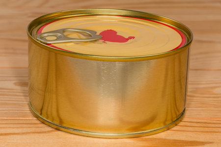 Canned turkey meat in the sealed round tin can with pull easy opened lid on the rustic table, side view close-upの写真素材