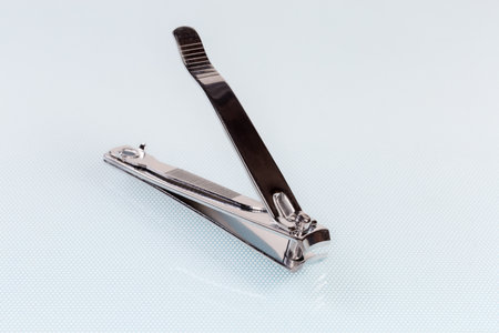 Stainless steel nail clippers in the compound lever design with fixed miniature file on the back end lie on a table, close-up in selective focusの写真素材