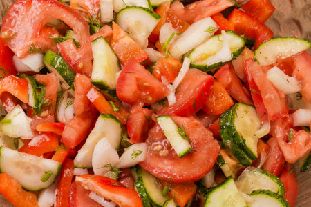 Vegetable salad made with fresh sliced tomatoes, red bell peppers, cucumbers and onion, top view close-upの写真素材
