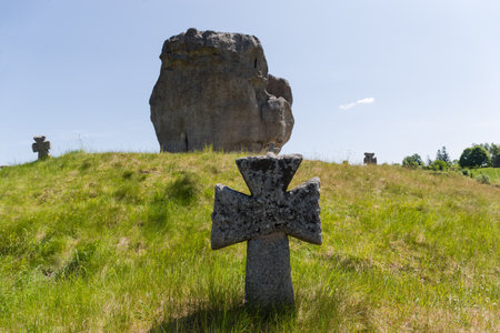 Old stone cross on the medieval Cossack grave on the hill overgrown with grass against the big single sandstone rock. Pidkamin village, Ukraineの写真素材
