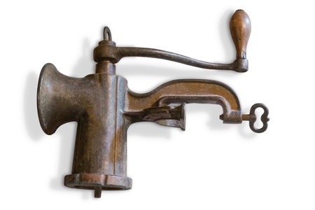 Old vintage hand-powered meat grinder assembled for use lying on a white backgroundの写真素材