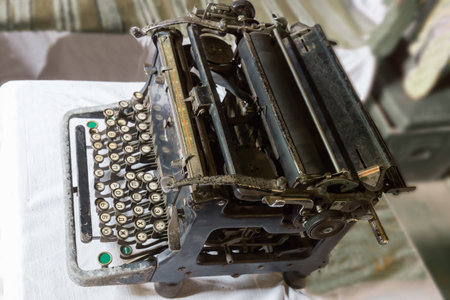 Old vintage mechanical desktop typewriter with Cyrillic type on a table covered with tablecloth, close-up in selective focusの写真素材