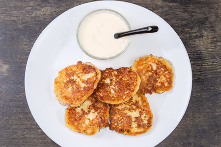 Cottage cheese pancakes with sour cream on dish, top viewの写真素材