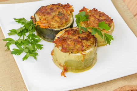 Baked pieces of zucchini stuffed with filling of the boiled rice with minced meat on the square dish, close-up in selective focusの写真素材