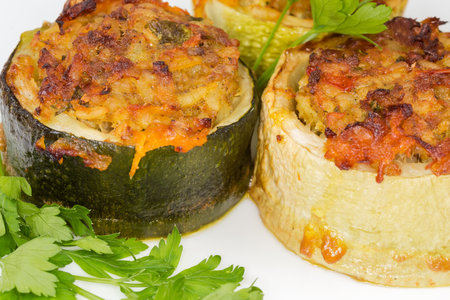 Baked pieces of zucchini stuffed with filling of the boiled rice with minced meat on the dish, fragment close-up in selective focusの写真素材