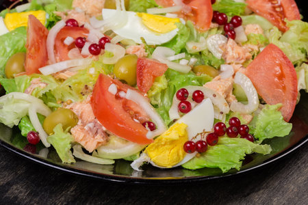 Lettuce salad with canned tuna, boiled eggs, different vegetables on the dish, fragment close-up in selective focusの写真素材