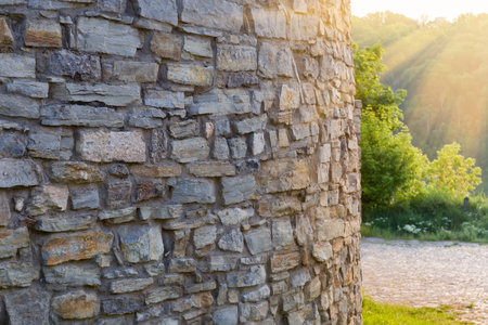 Fragment of the rounded wall of the mediaeval defensive building made with rough stones in sunny morning backlitの写真素材