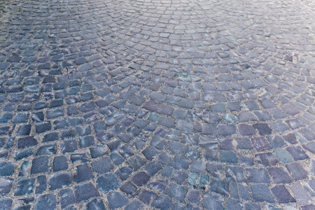 Fragment of the ancient road paved by the old stone sett paving in early morning