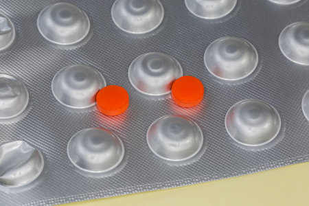 Two red pills pills of the medication lie on the foil blister pack, close-up in selective focusの写真素材