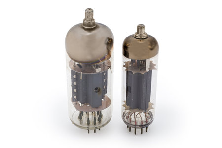 Two different old electronic vacuum tubes with top caps connections for higher voltages on the anodes are stand on a white backgroundの写真素材