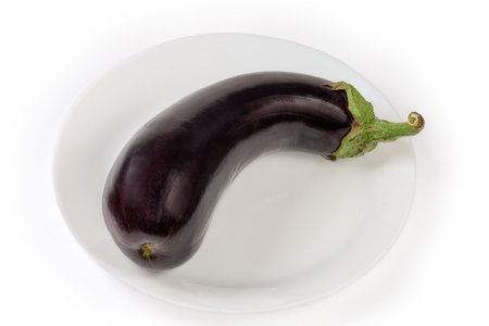 Freshly harvested ripe whole purple eggplant on the white dish on a white backgroundの写真素材