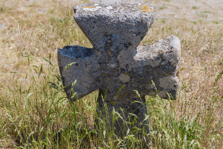Old stone cross among the grass on the medieval Cossack grave on the hillside in sunny dayの写真素材