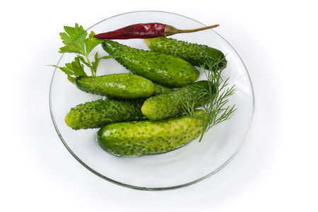 Semi-pickled, or lightly salted cucumbers and gherkins made with short-term salting method on the glass saucer on a white backgroundの写真素材
