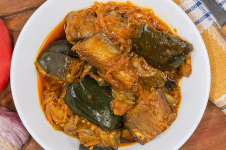 Eggplant pieces stewed with other vegetables in the white bowl, top view close-upの写真素材