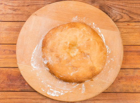 Baked whole thick lush Georgian lavash on a big round board sprinkled with flour on the rustic table, top viewの写真素材