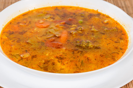 Spicy vegetable red soup in the white bowl, side view of the soup surface close-up in selective focusの写真素材