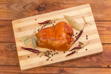 Boiled-smoked pork ham hock among the different dried spices on cutting board on the rustic table, top viewの写真素材